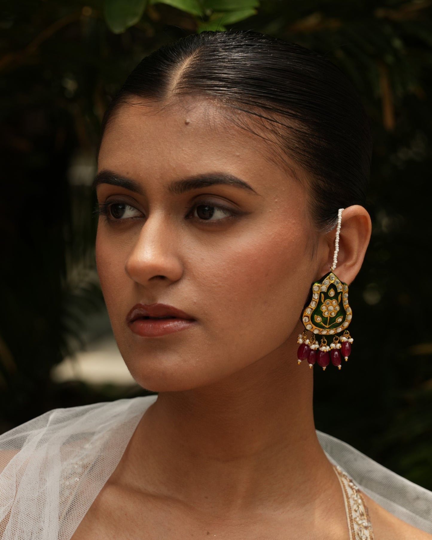 Close-up of emerald green Meenakari jadau earrings with kundan, pearls, jade and kaan chain – Indian handmade jewelry